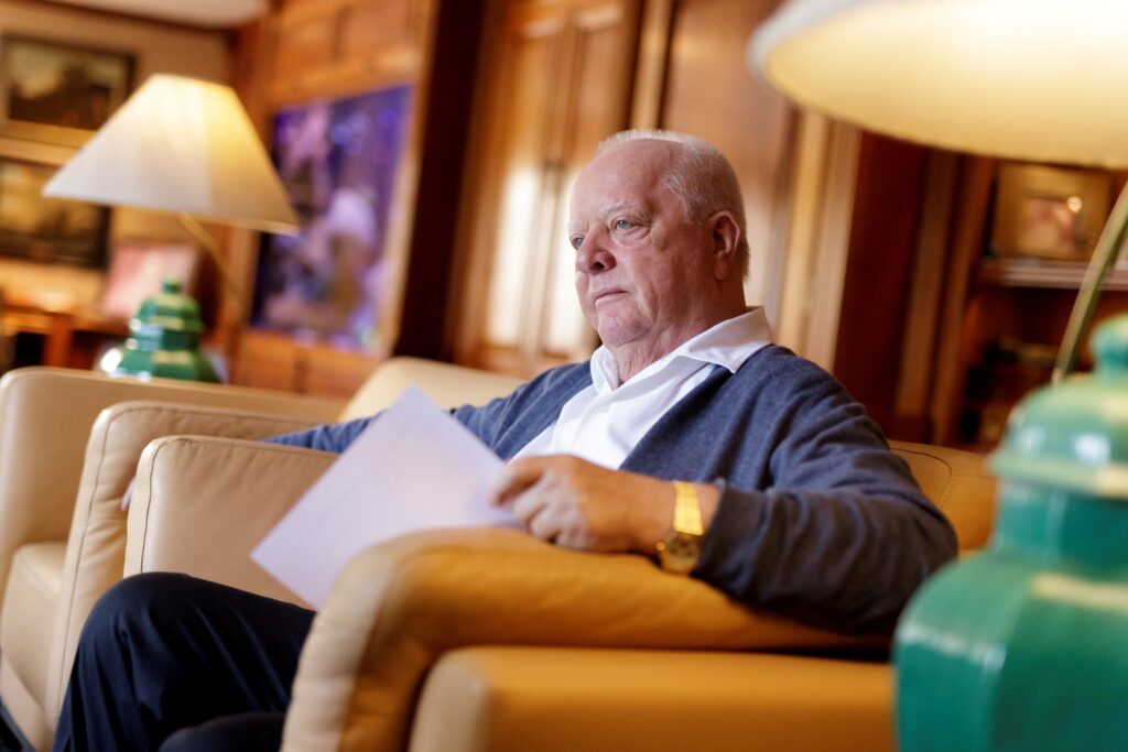 El Sr. Wolfgang Kiessling, presidente de Grupo Loro Parque, aparece sentado en un sillón de su despacho, concentrado y sosteniendo documentos, en el contexto de la demanda interpuesta contra la Autoridad Científica Española (CITES) por presunta falta de transparencia en sus decisiones relacionadas con la conservación de especies.